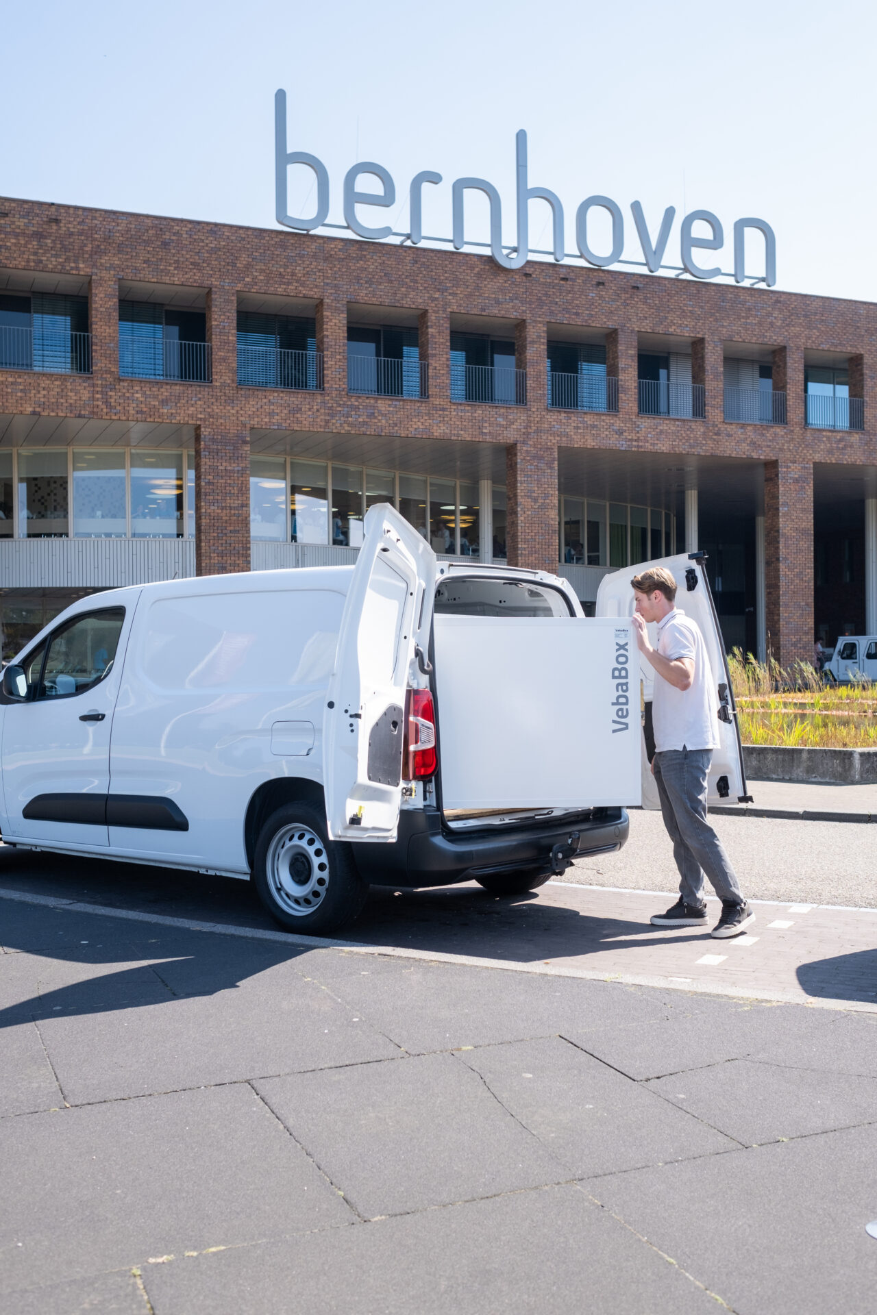 Mitarbeiter öffnet einen VebaBox-Kühlbehälter in einem weißen Lieferwagen zur frischen Blumenlieferung an einen Kunden.