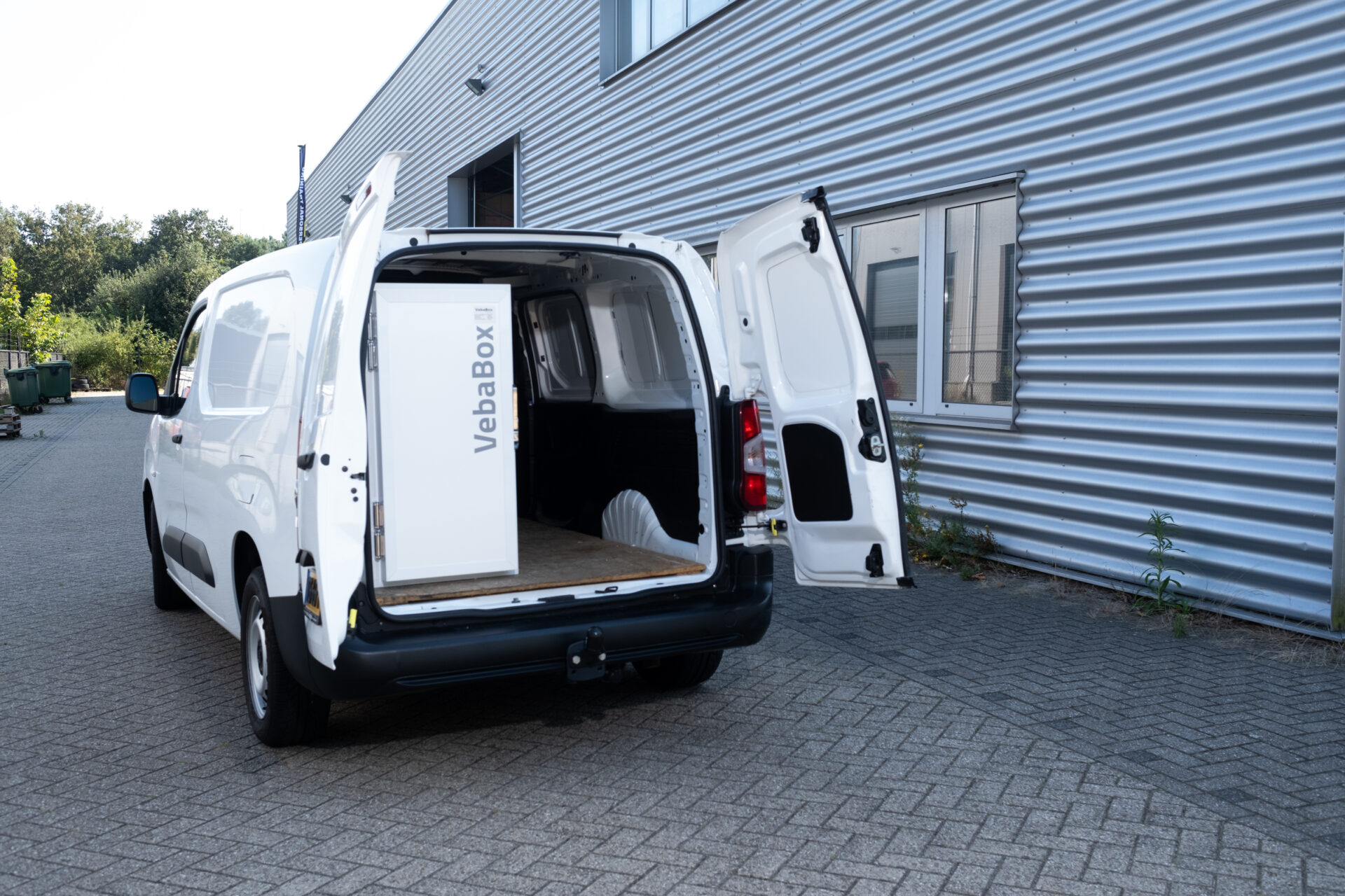 Heckansicht eines weißen Lieferwagens mit geöffneten Türen und eingebauter VebaBox-Kühlbox.