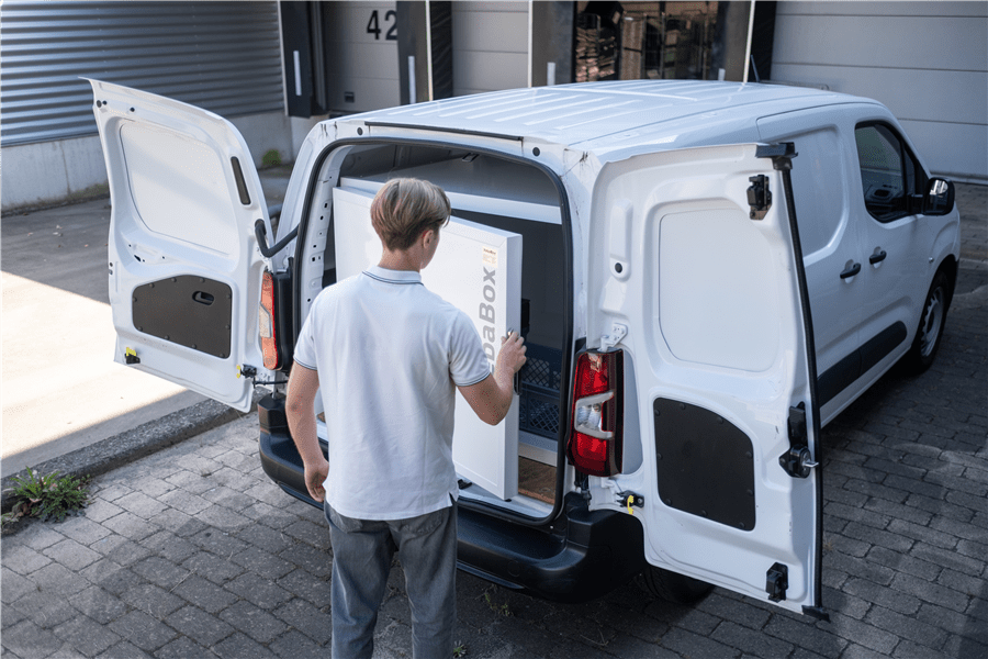 Mitarbeiter platziert eine VebaBox Kühleinheit in einem weißen Transporter an einer Laderampe.