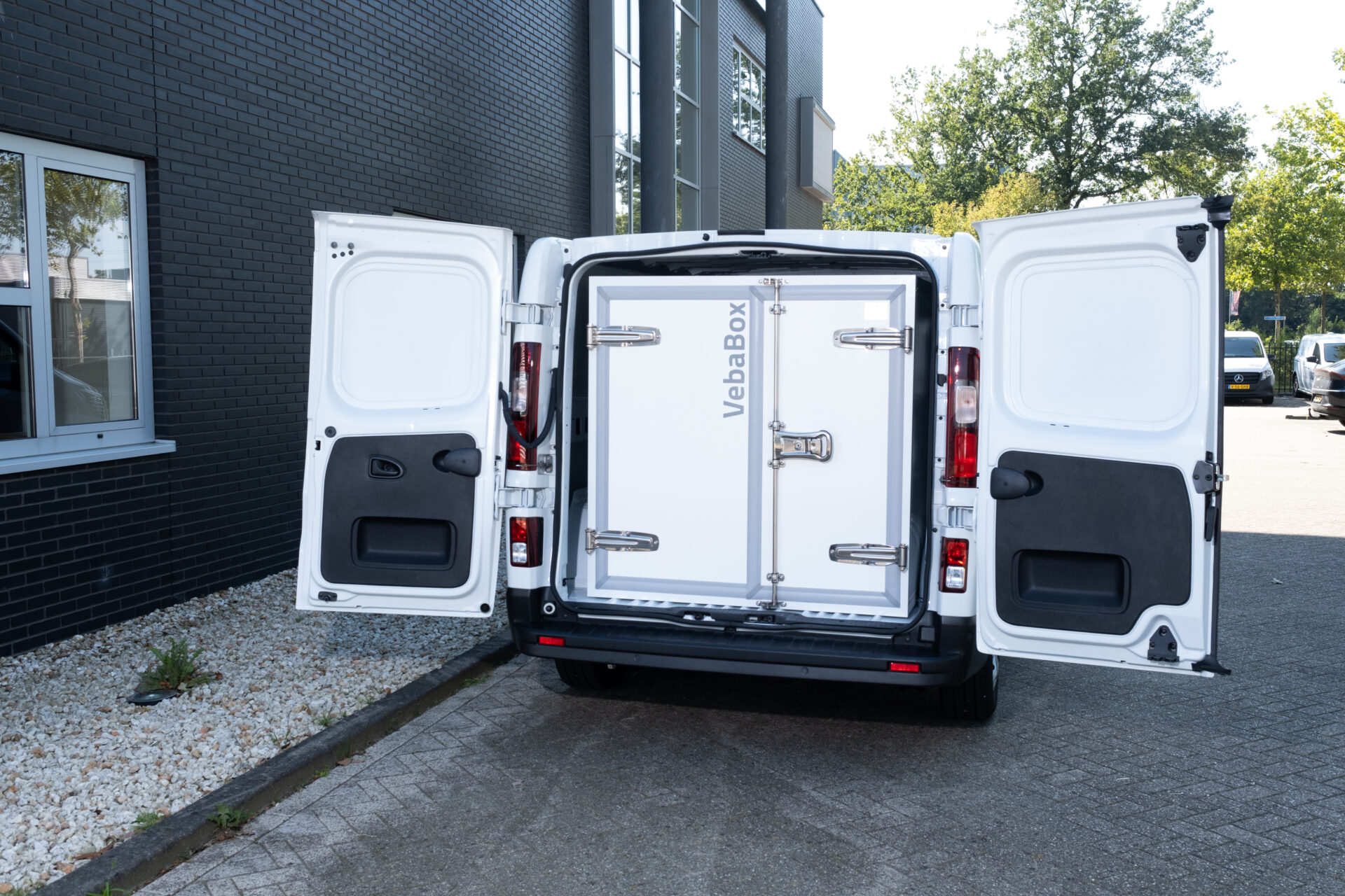 Weißer Transporter mit aufgeklappten Hecktüren, in dem eine VebaBox-Kühleinheit eingebaut ist.