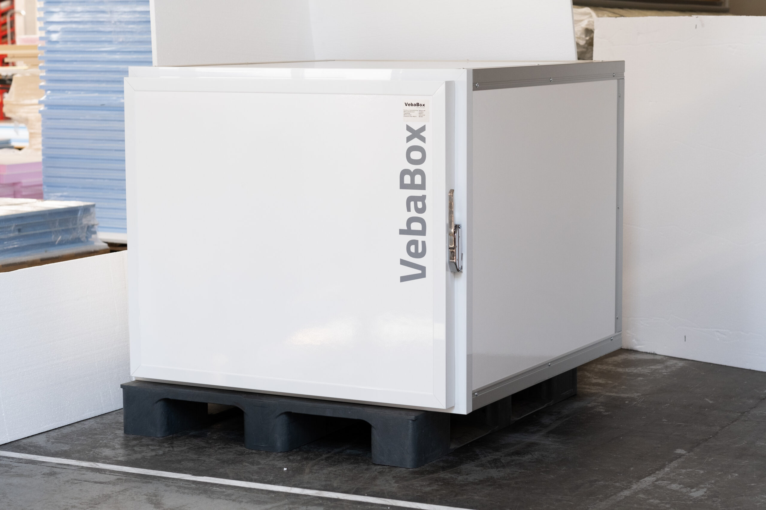 Weiße VebaBox Kühlbox auf Palette in Lagerumgebung, bereit als mobile Kühllösung für den Kühltransport.